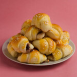 A plate holding crescent rolls on a pink background..