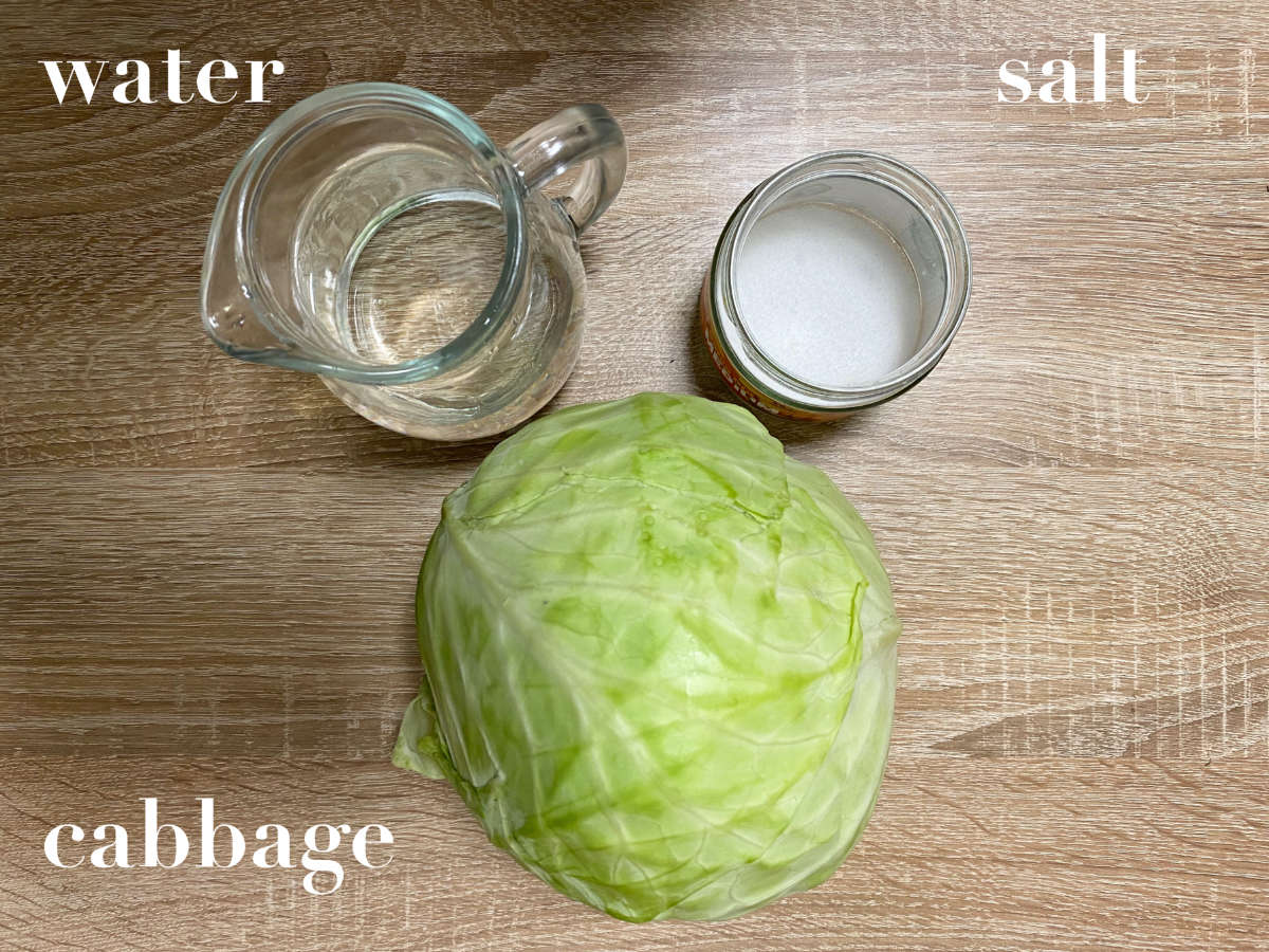 Green cabbage head, salt and water on wooden table. 