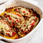 Four stuffed eggplants in a baking pan.