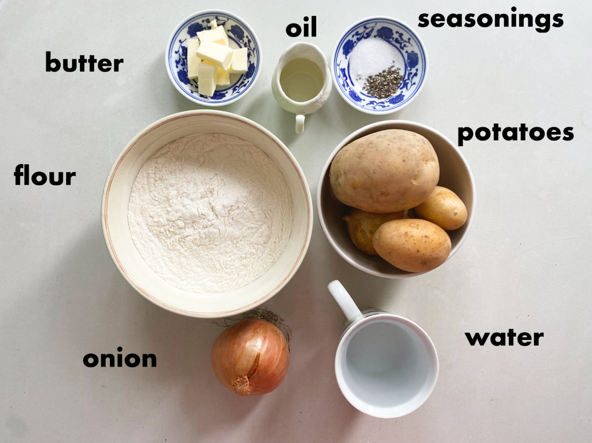 Ingredients from above on a white background (seasonings, potatoes, water, onion, flour, butter and oil.