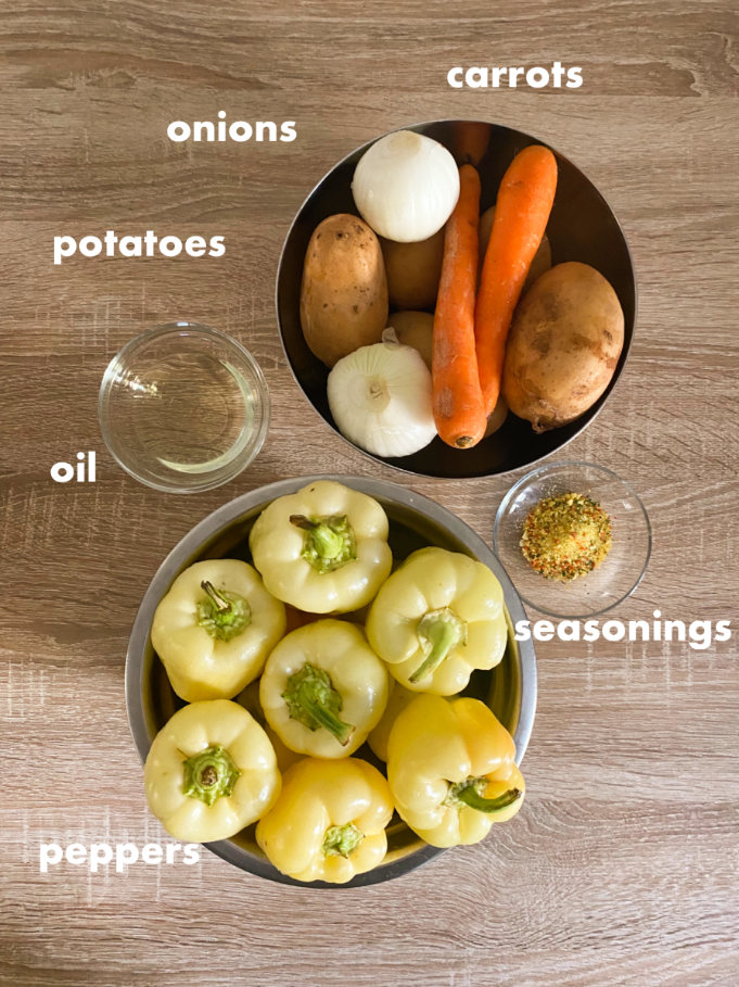 Two stainless steel bowls and two glass bowls holding ingredients on a table (oil, seasonings, carrots, onions, potatoes, peppers). 