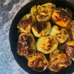 Overhead of a black baking pan full of stuffed peppers on a marble gray background.