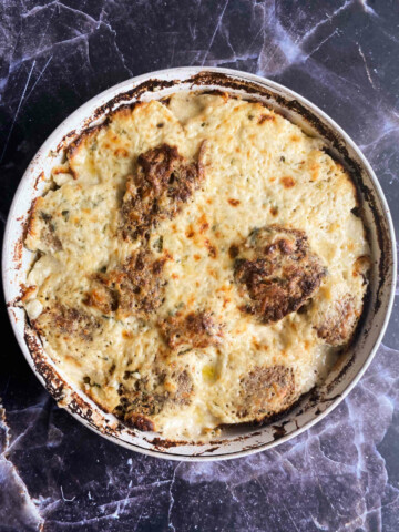 A pan with patties in bechamel on a blue marble background, overhead photo.