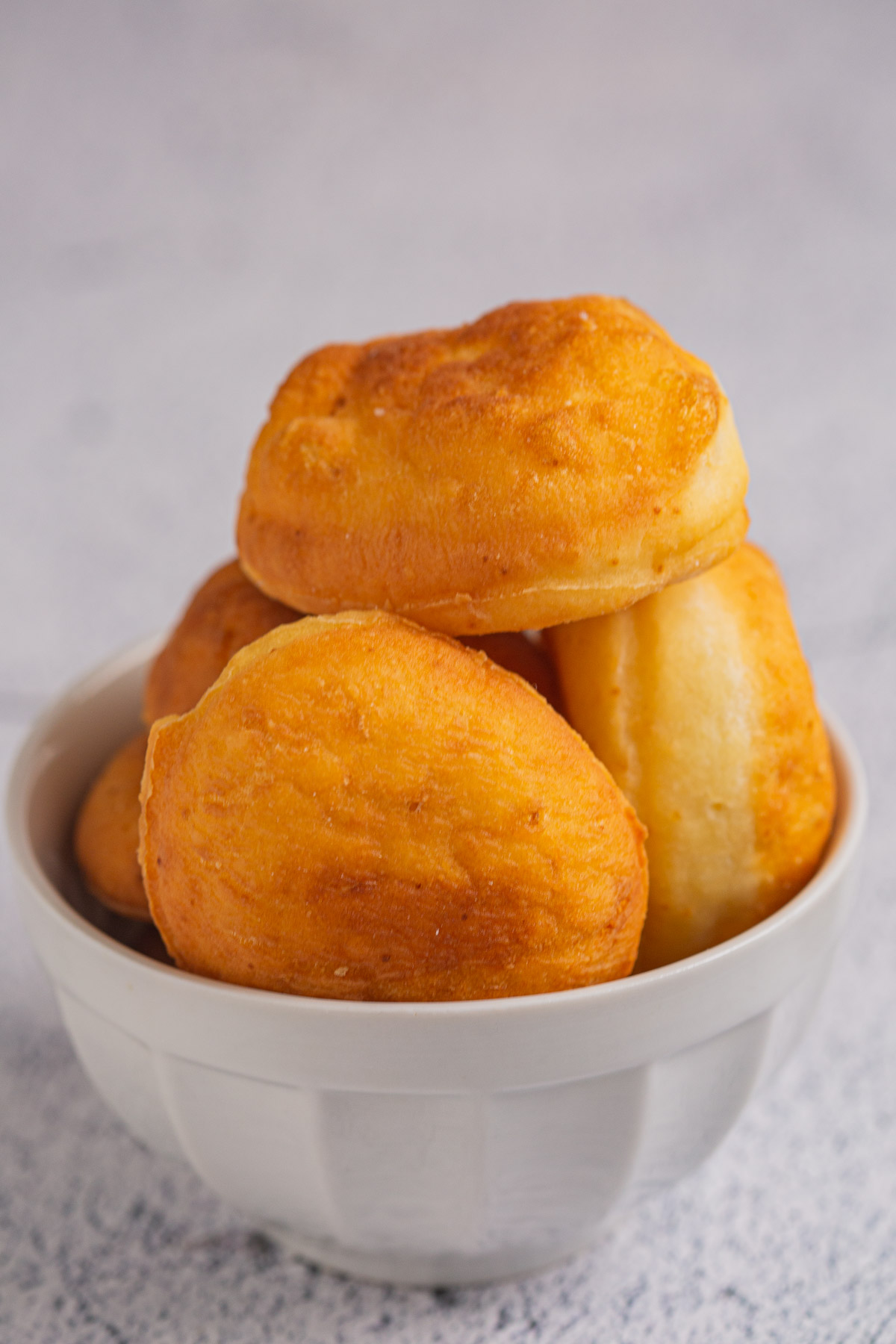 Four dough balls in a white bowl on gray background. 