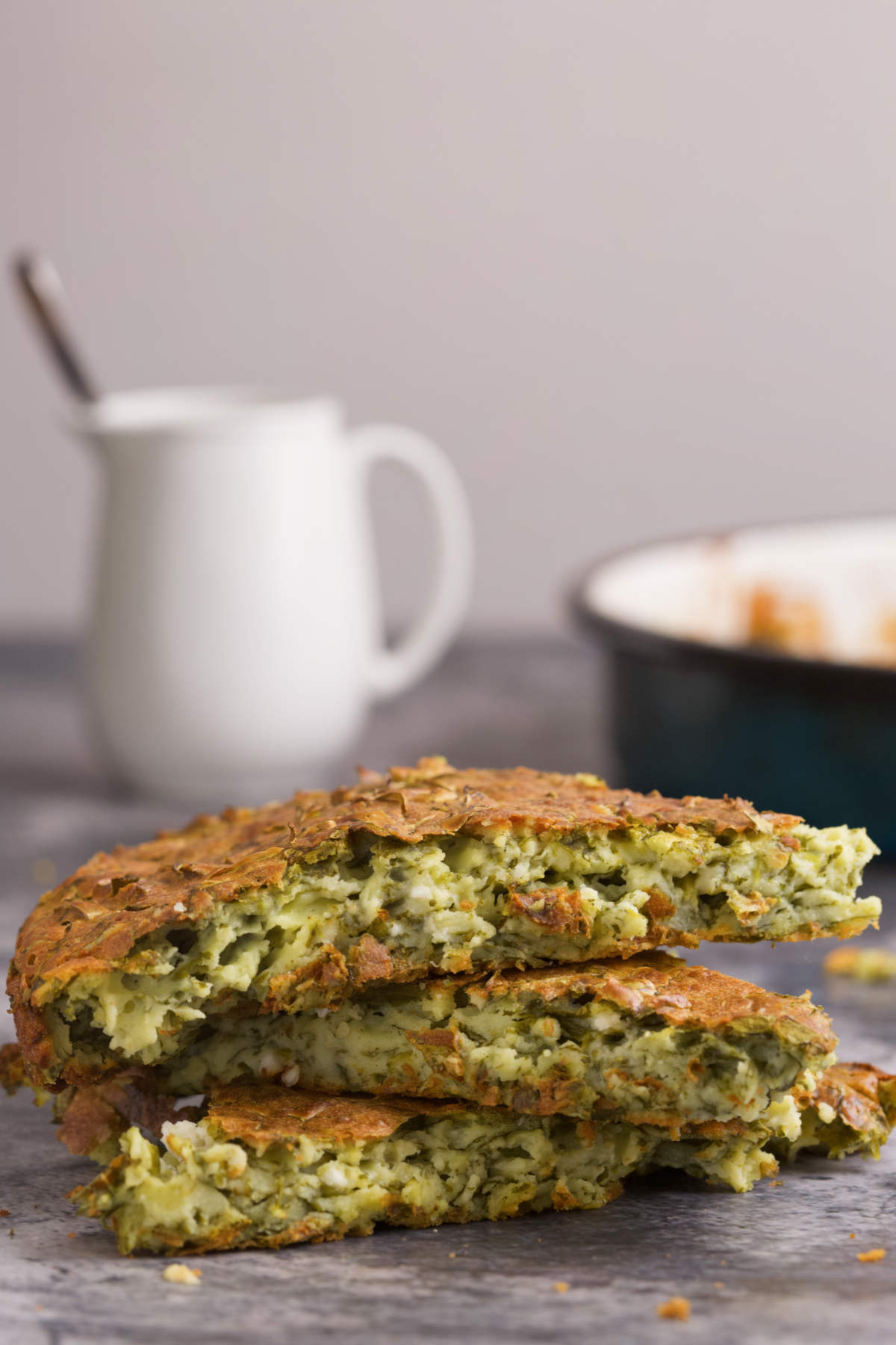 Three  pieces of quiche in front of a jug and pan.