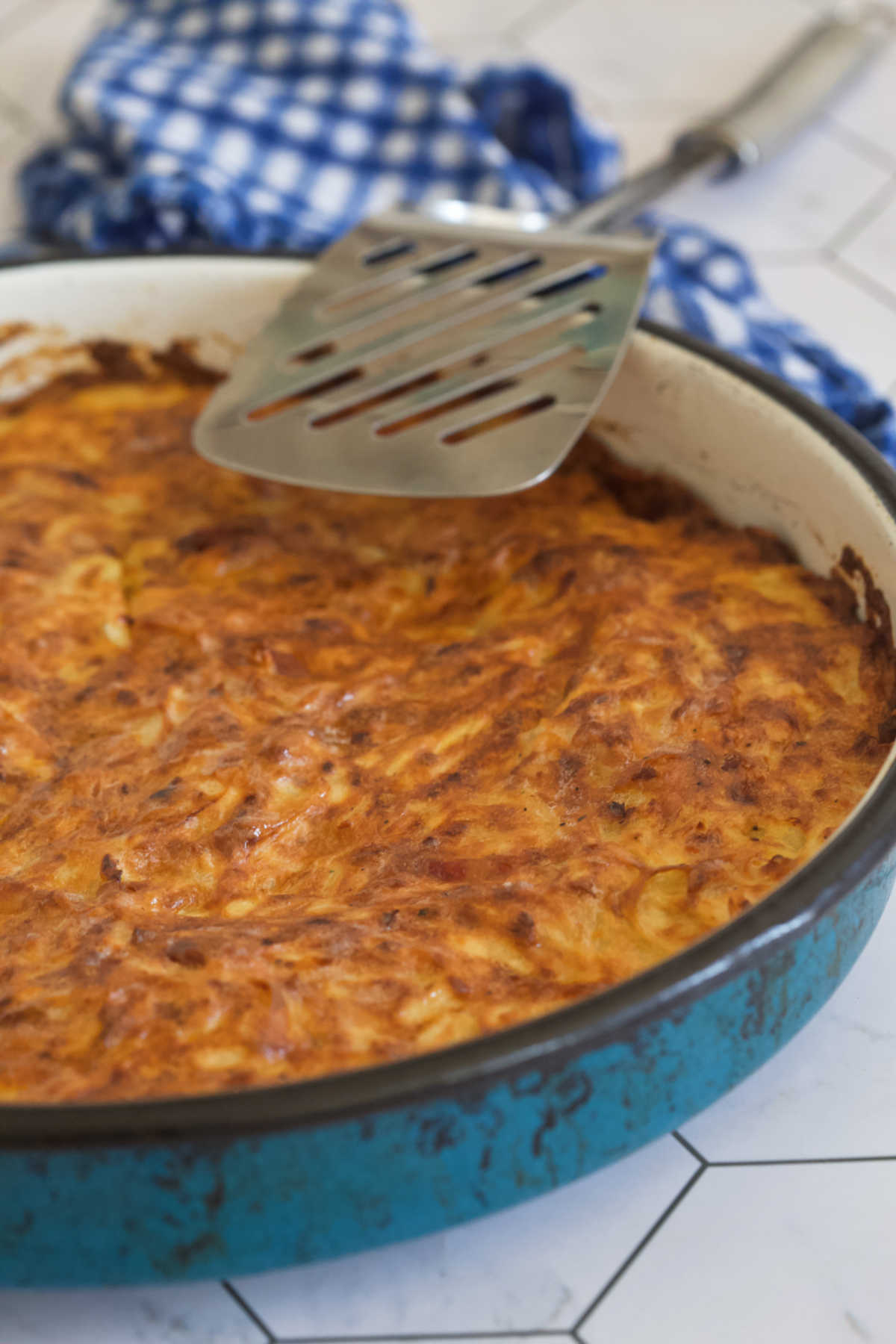 Blue pan with pie inside and a spoon utensil. 