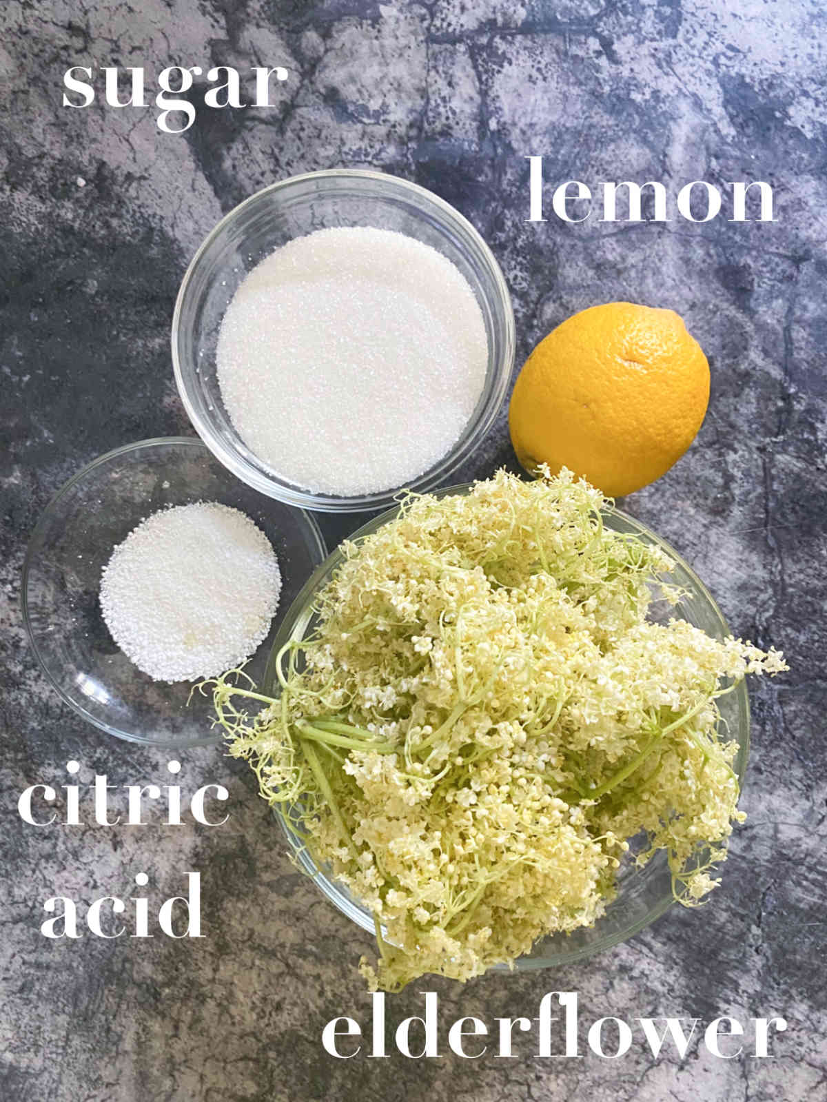 Lemon, elderflowers, citric acid on a marble background.