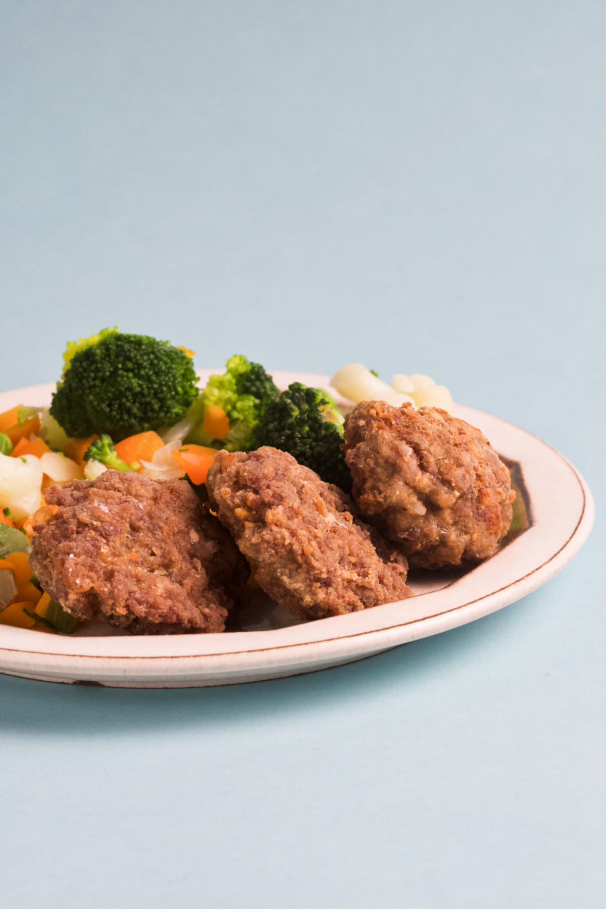 A plate filled with rissoles on a blue background.