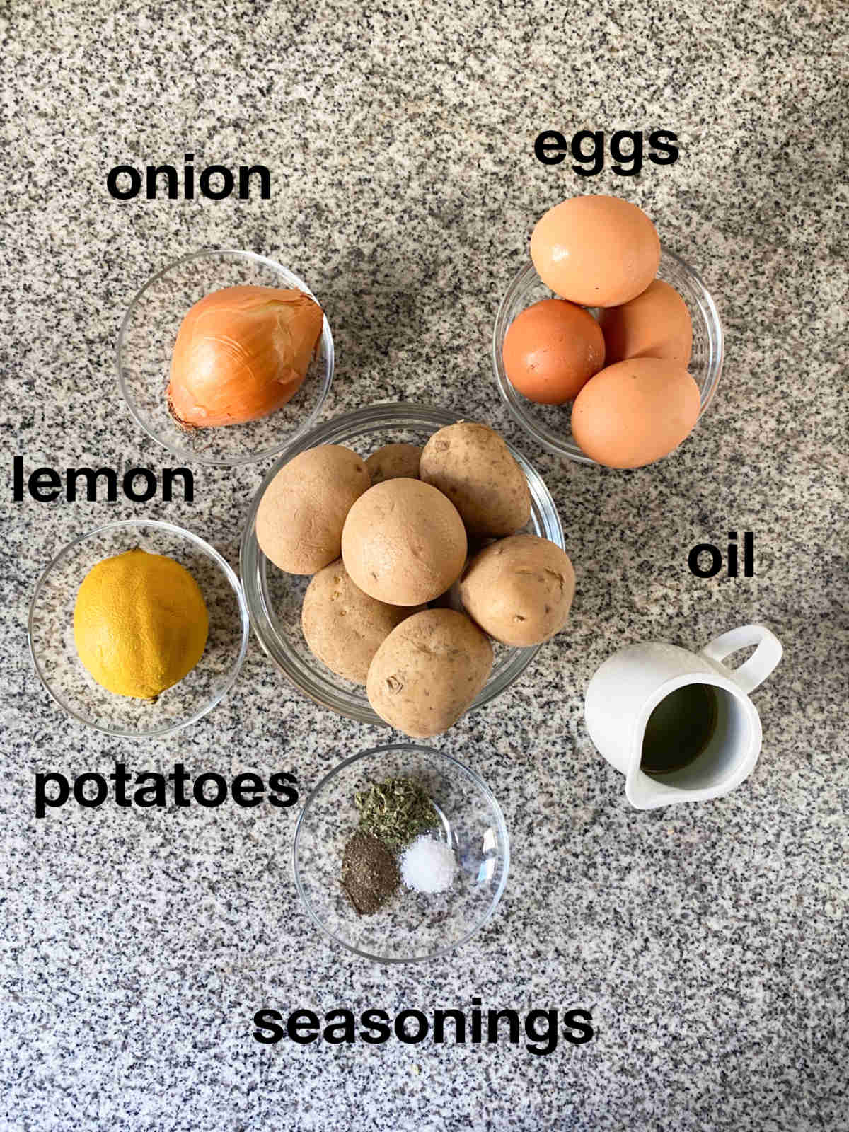 Onion, eggs, lemon, potatoes, seasonings and oil on a granit background, overhead photograph.