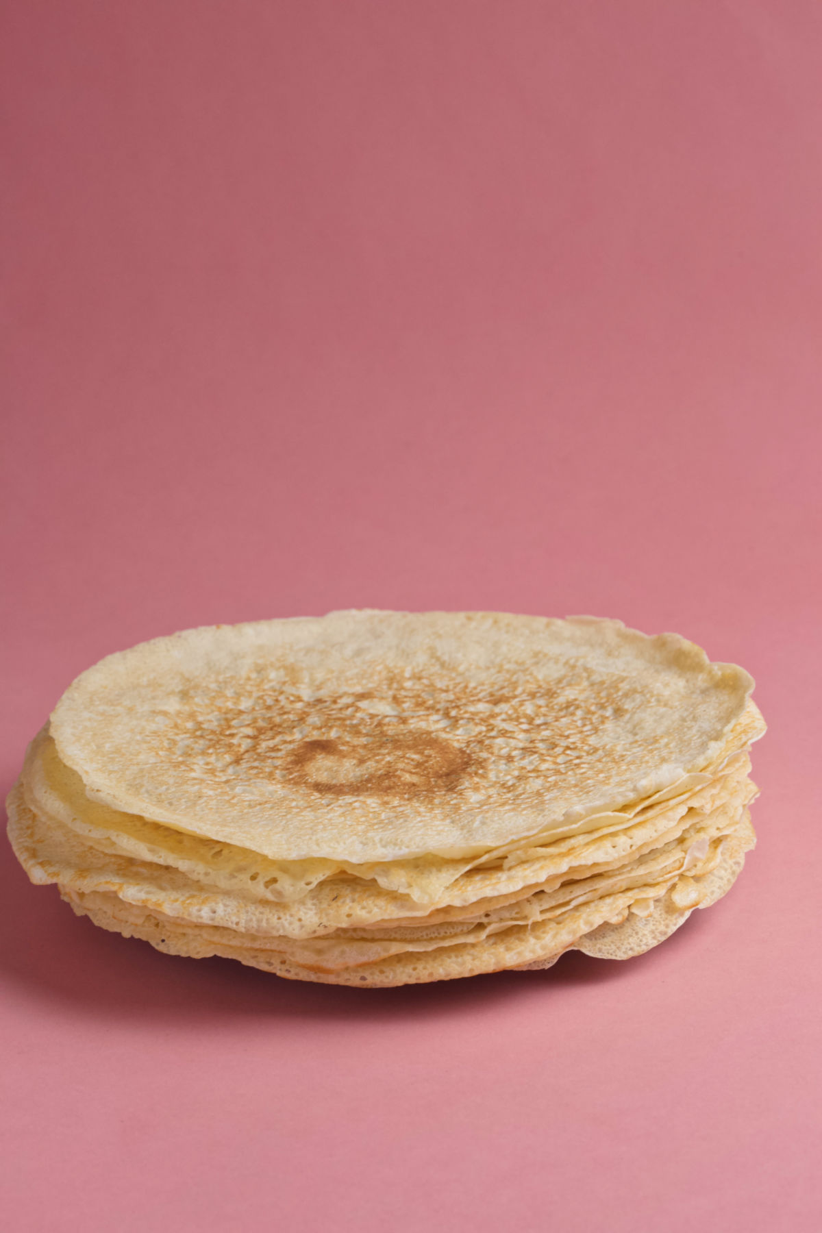 A plate of crepes on a pink background.