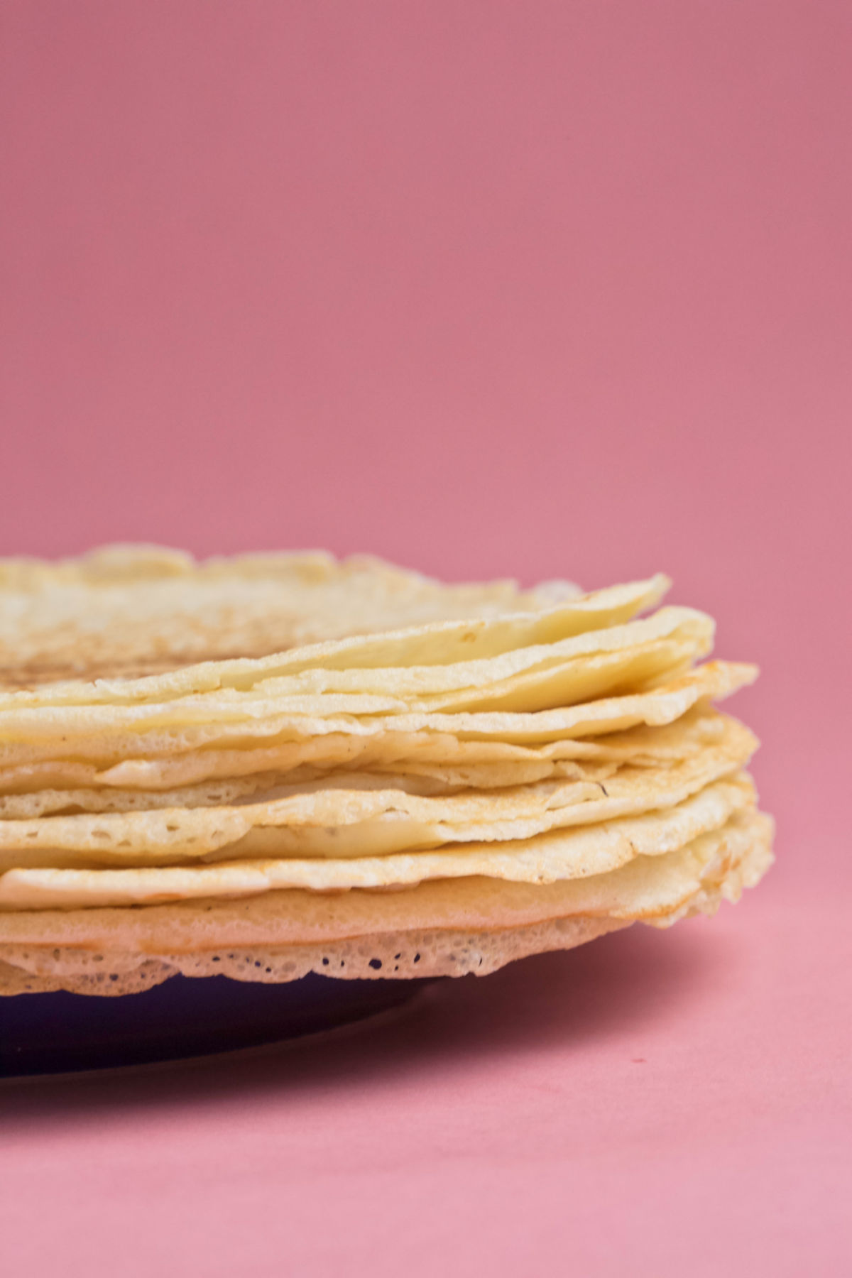 A plate of crepes on a pink background.