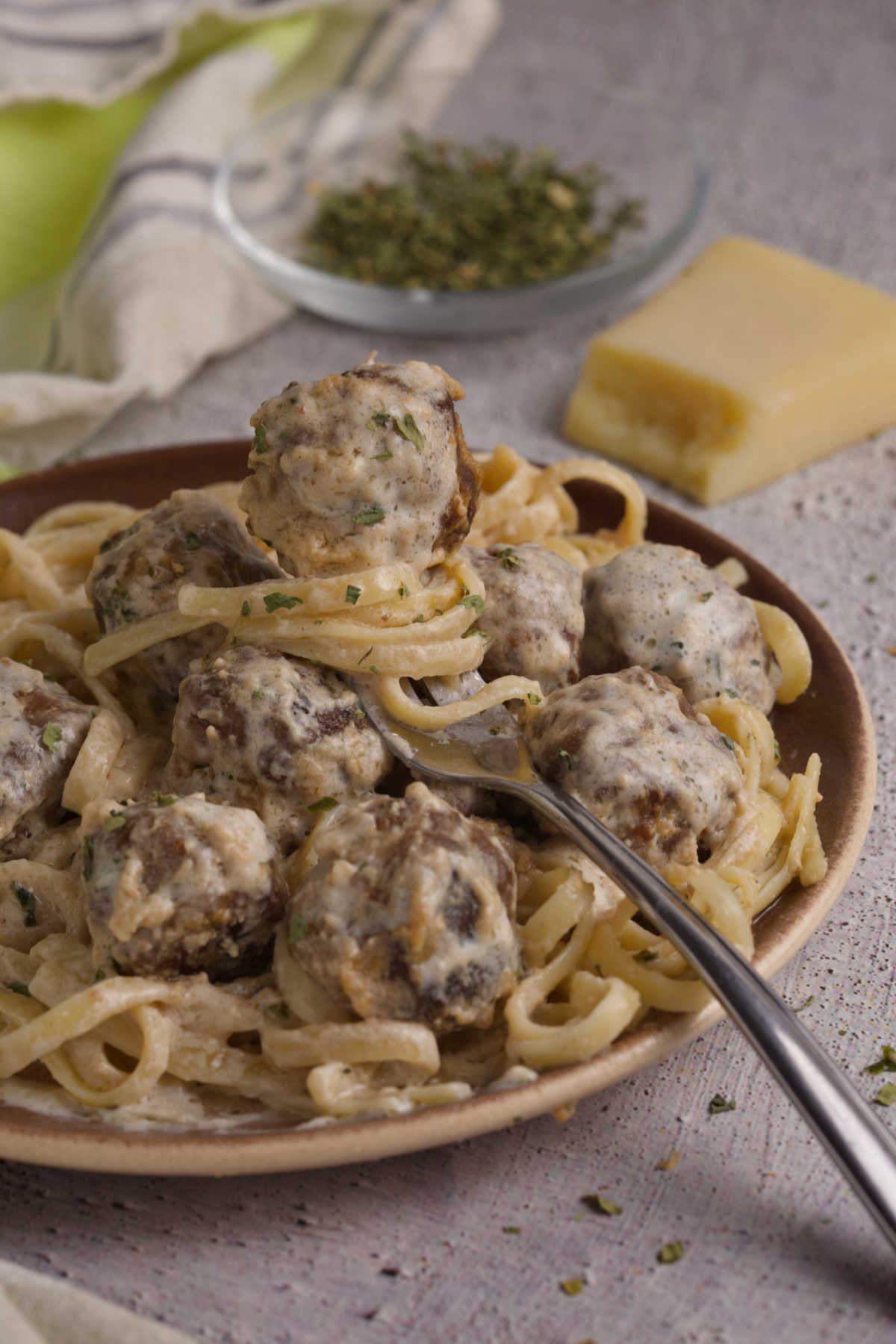 Plate full of meatballs and linguini, and a fork with a meatball. 