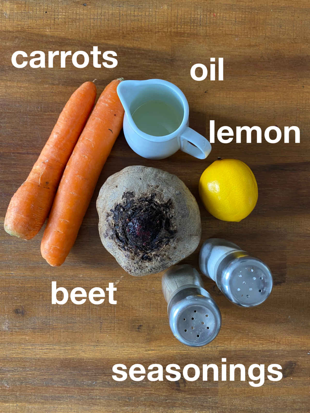 Carrots, beet, seasonings, lemon and oil on a table, overhead photograph.