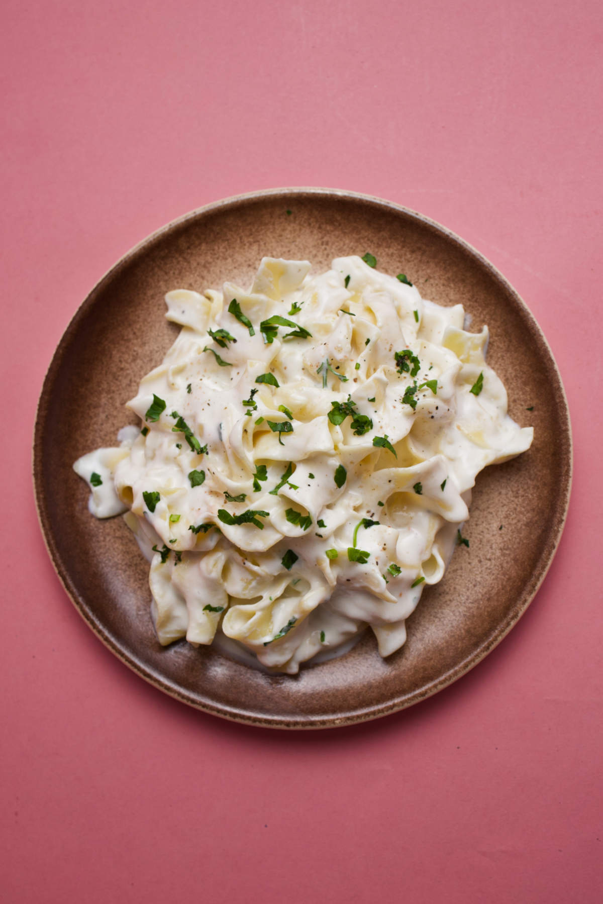 Milk pasta on a plate on a pink background, overhead photo. 