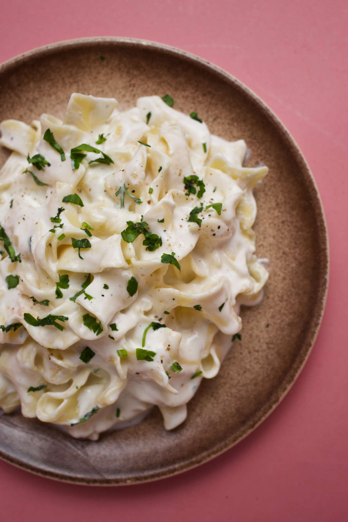 Overhead photo of milk pasta on a plate on a pink background. .