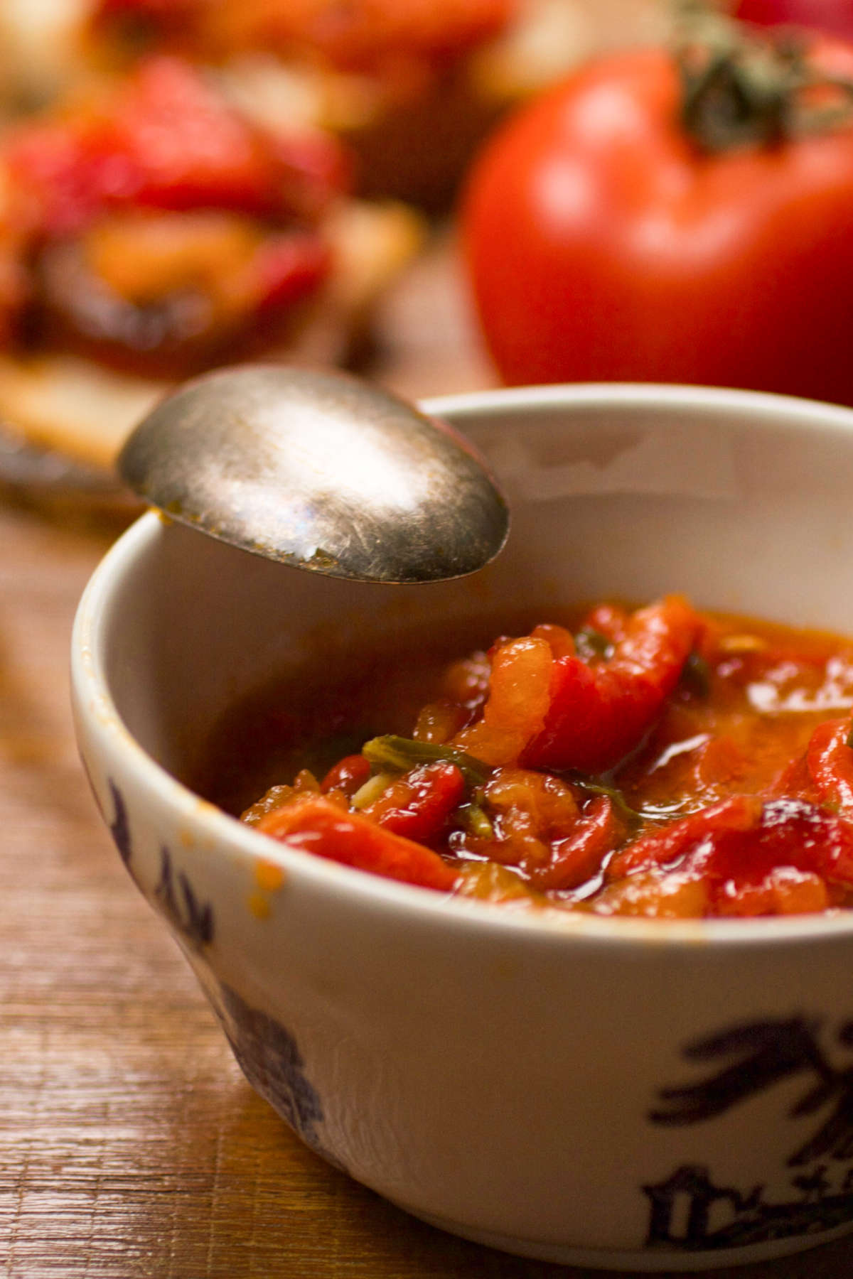 PIndjur in a bowl on a table with vegetables in the background.