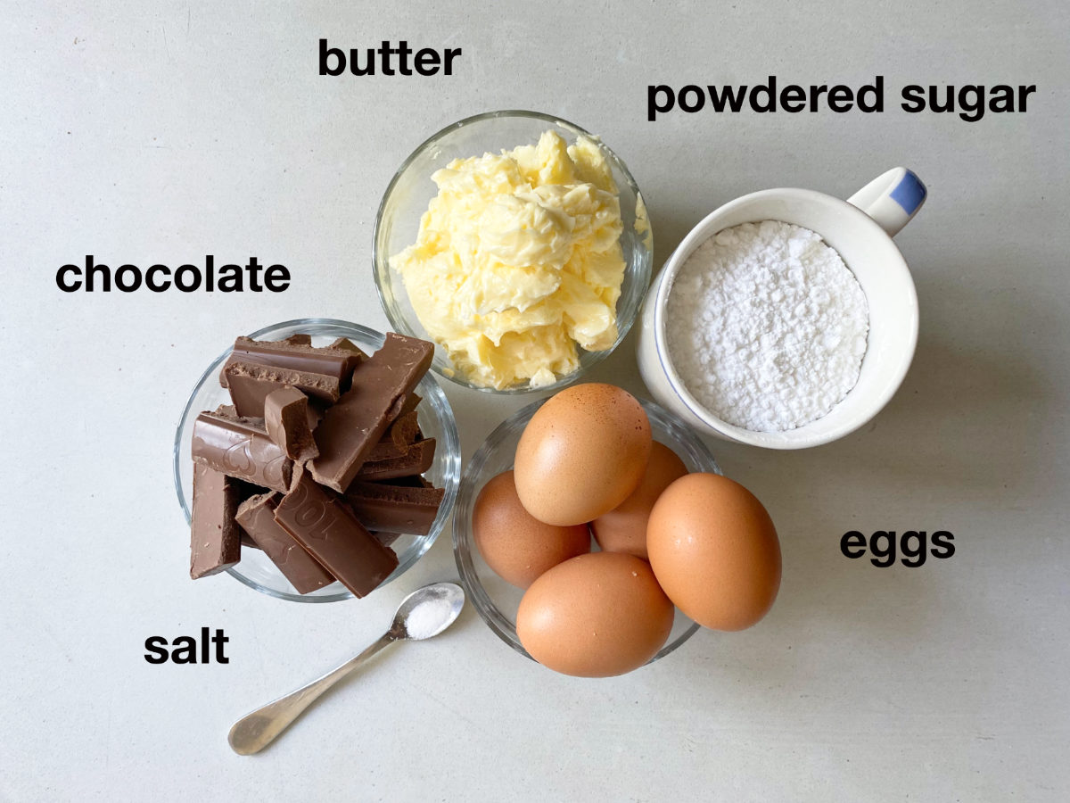 Ingredients for cake filling on white background: chocolate, butter, powdered sugar, eggs, salt. 