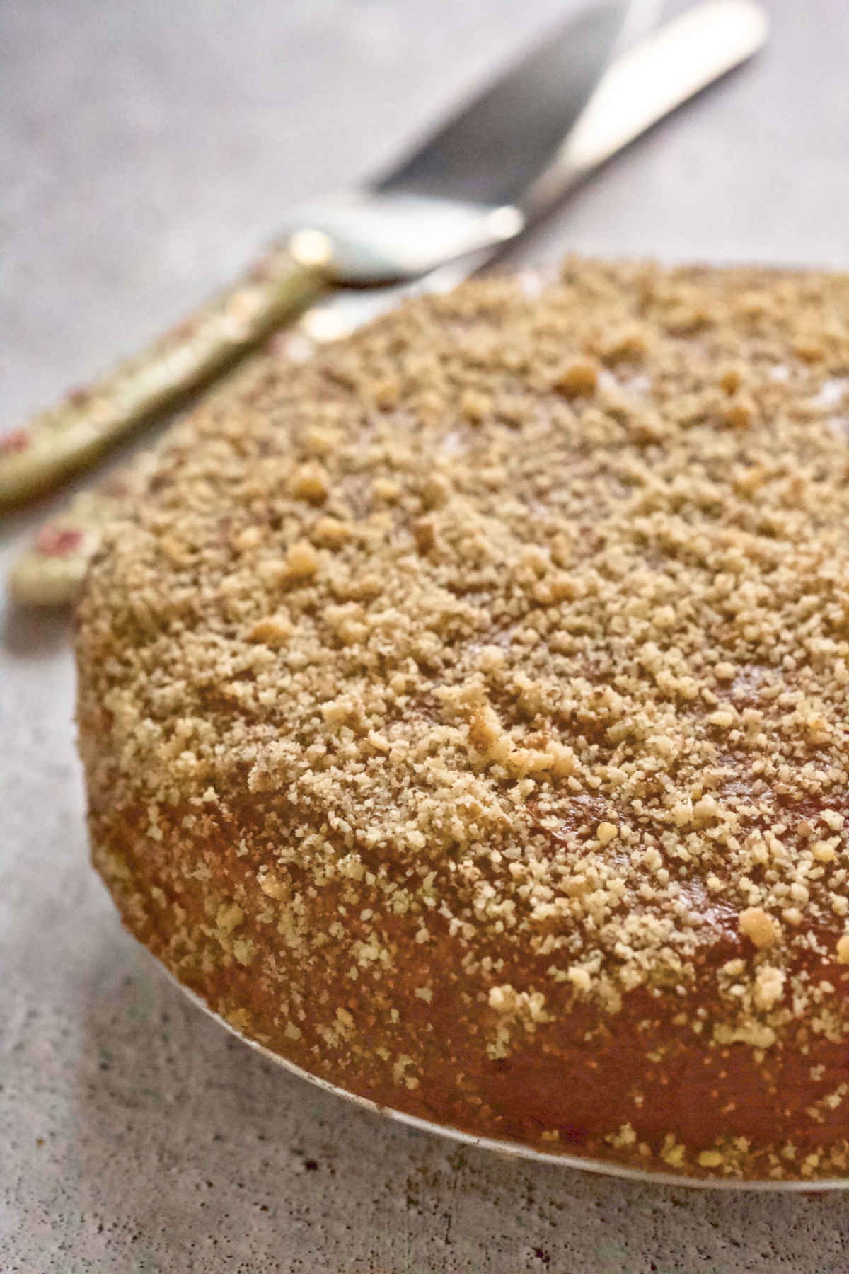 Cake on a plate on a white background an cutting utensils in the back.