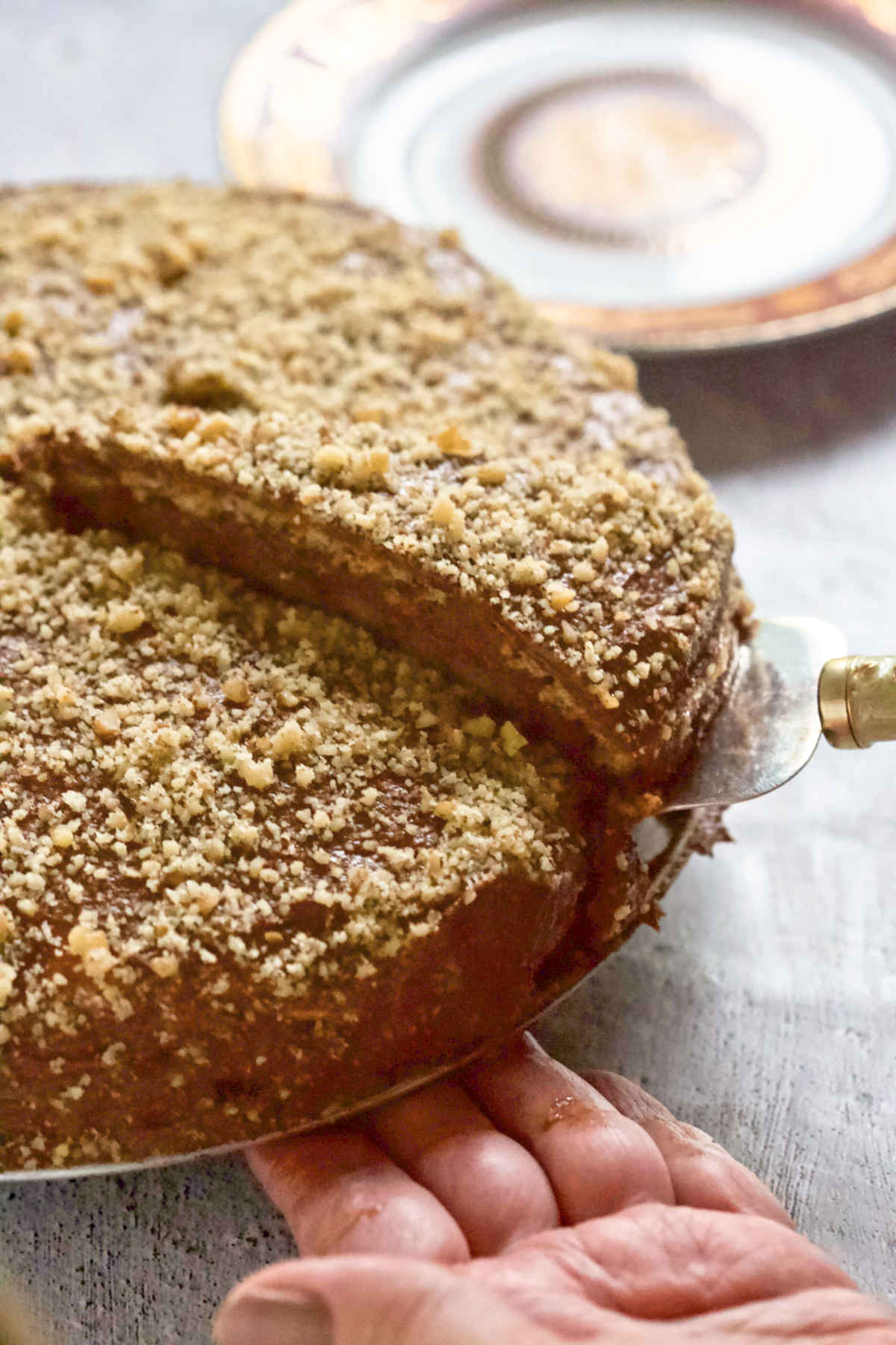 Cake being cut and a hand holding it on the bottom.