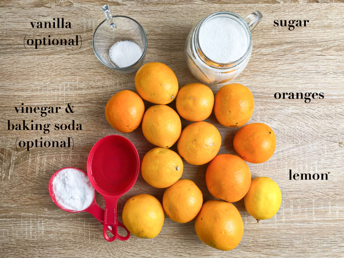 Oranges, lemon, sugar, vanilla, vinegar and baking soda on a wooden table, overhead.