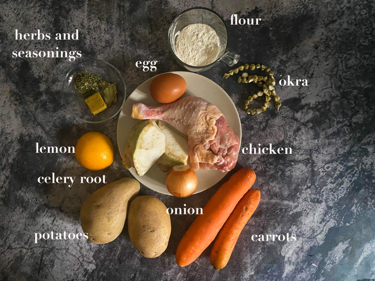 Ingredients (onion, flour, seasonings, herbs, egg, chicken, carrots, okra, flour, potatoes and celery) on a gray marble background. 