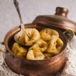 Stuffed cabbage on a spoon in a copper pot.