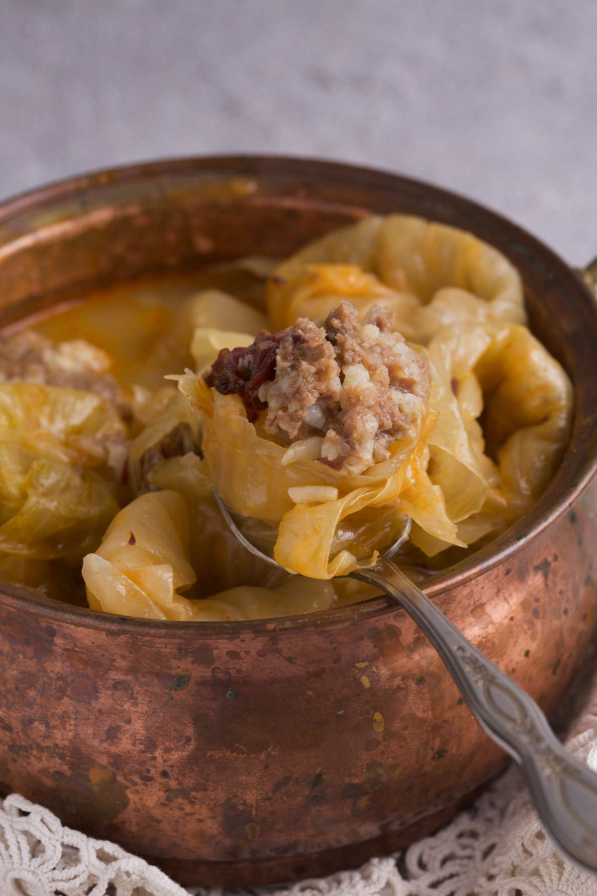 A pot filled with stuffed cabbage and a spoon. 