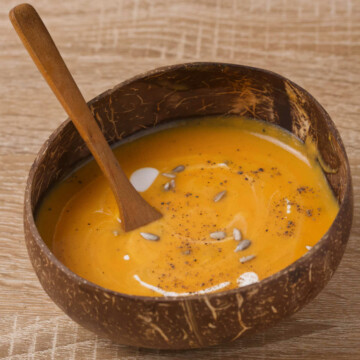 Soup in a wooden bowl with a wooden spoon on a wooden table.