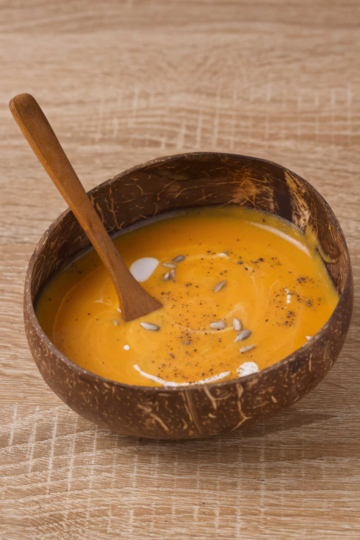 Soup in a wooden bowl with a wooden spoon on a wooden table.
