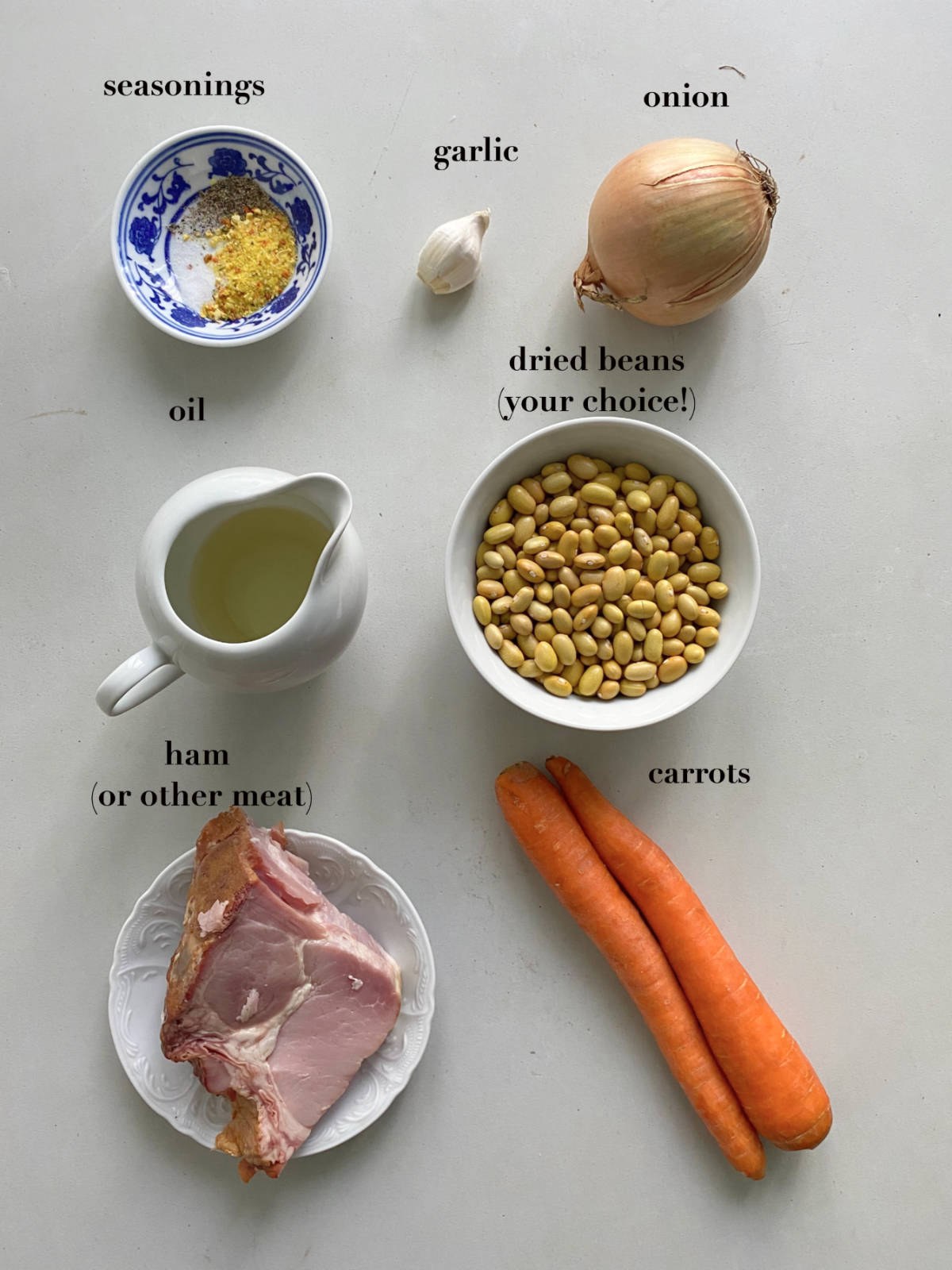 Stew ingredients (seasonings, meat, beans, etc) on a gray background.