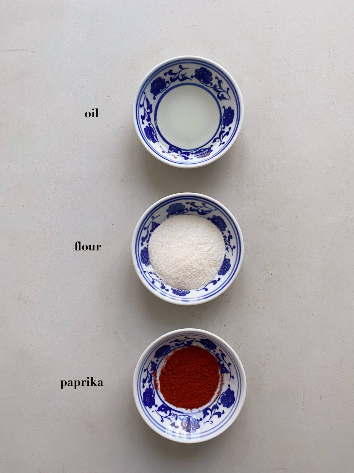 Oil, flour, paprika in ceramic containers on a gray background.