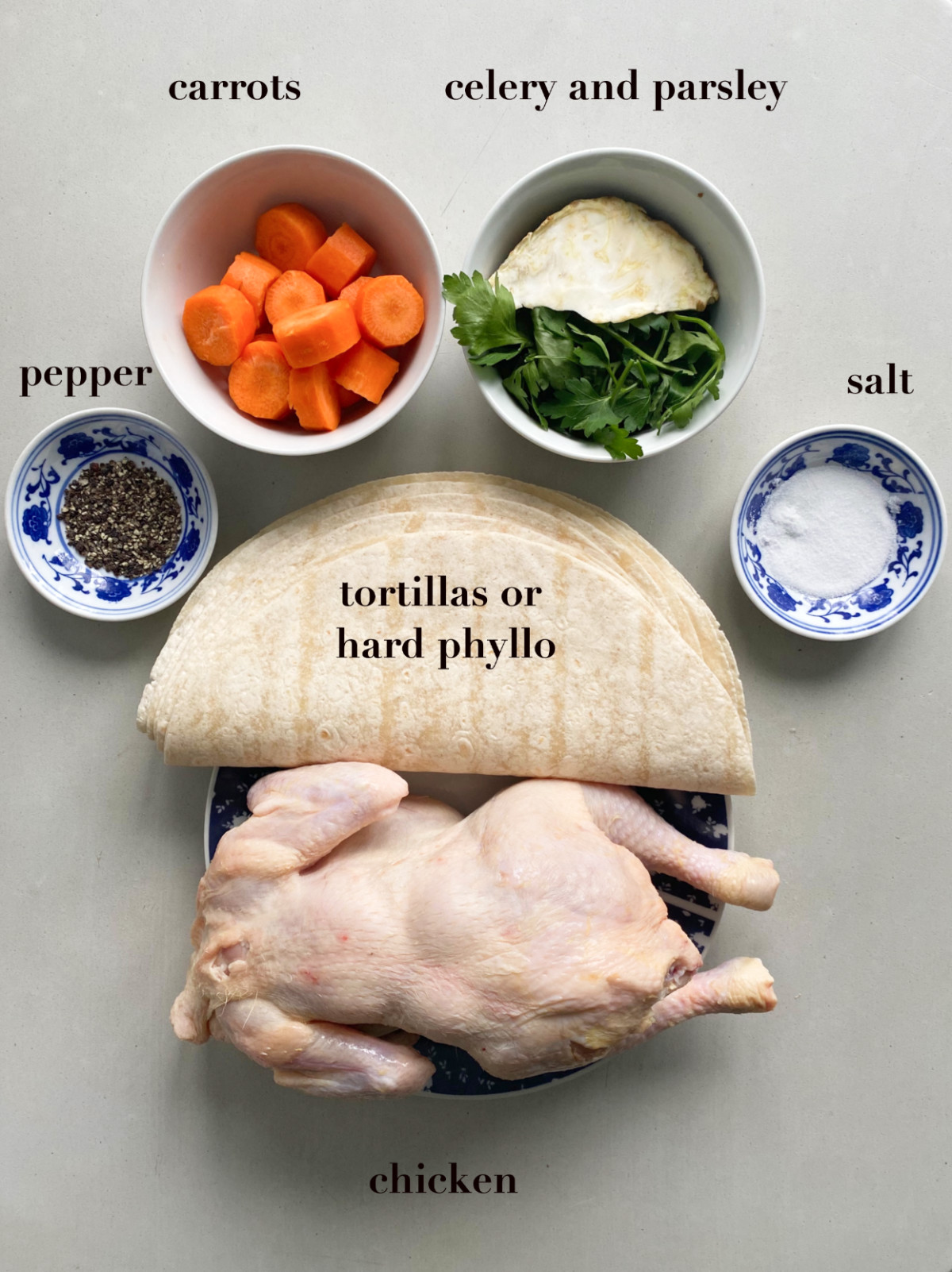 Ingredients on a table; chicken, tortillas, carrots, parsley, salt and pepper.