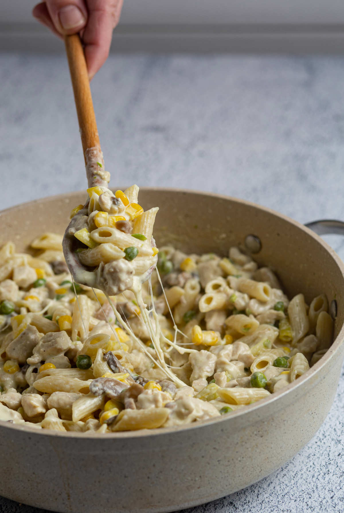 Pan of pasta and a spoon taking some of it out.