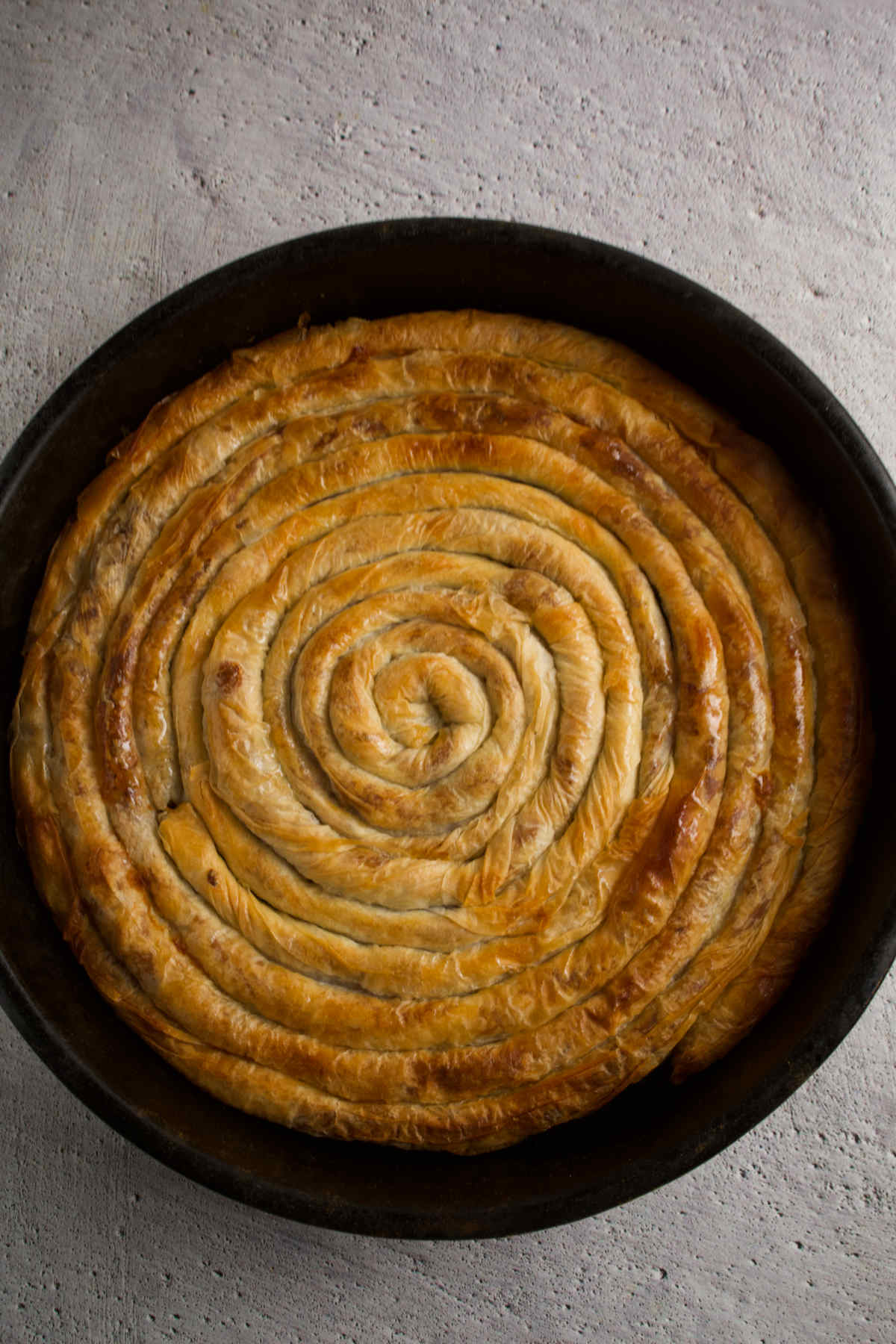 Burek pie in a pan on a gray background. 