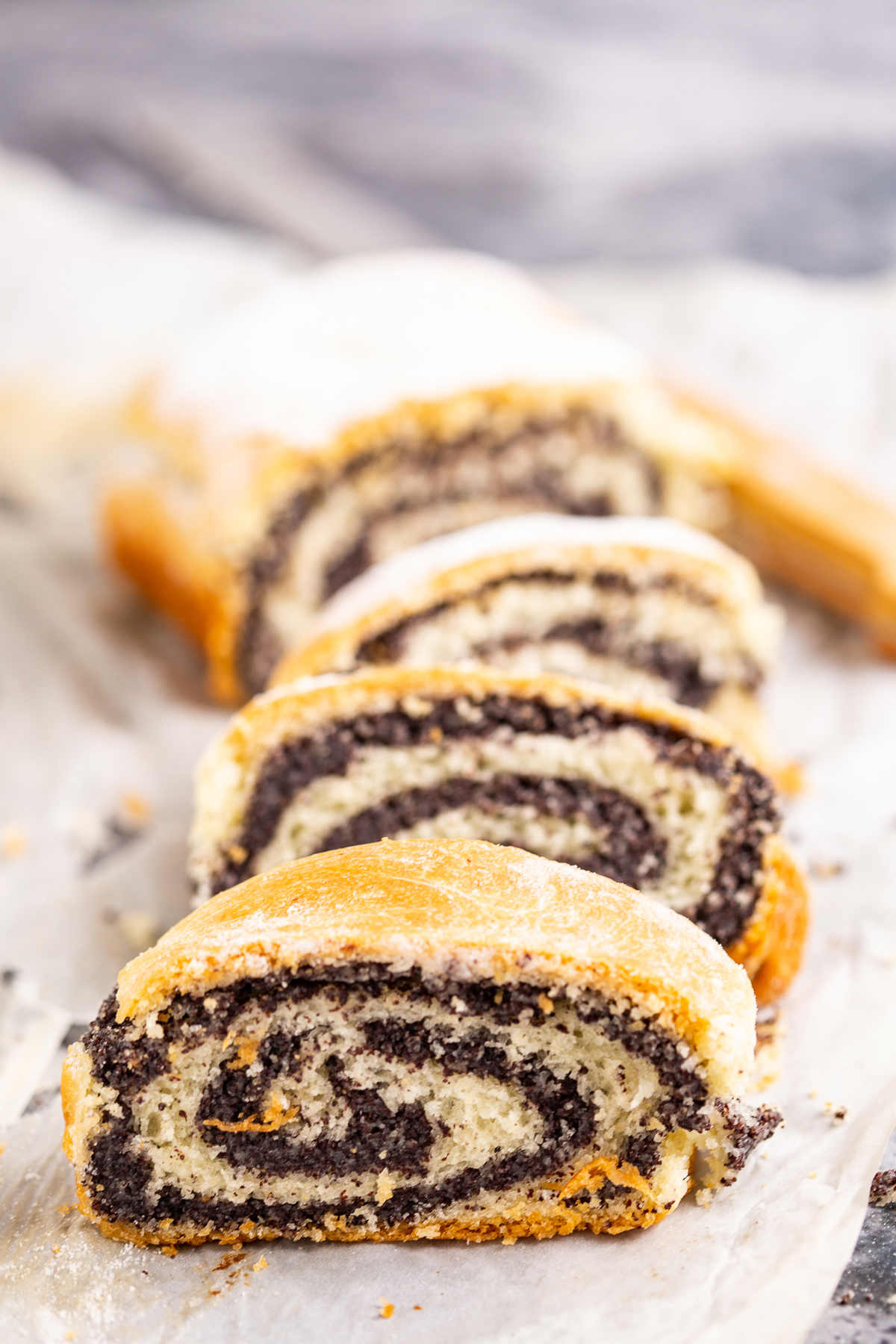 Four pieces of poppy seed roll and a knife.