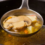 A ladle full of mushroom and potato soup.