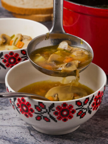 Two bowls of soup, and a ladle full of soup pouring it into one of the bowls.