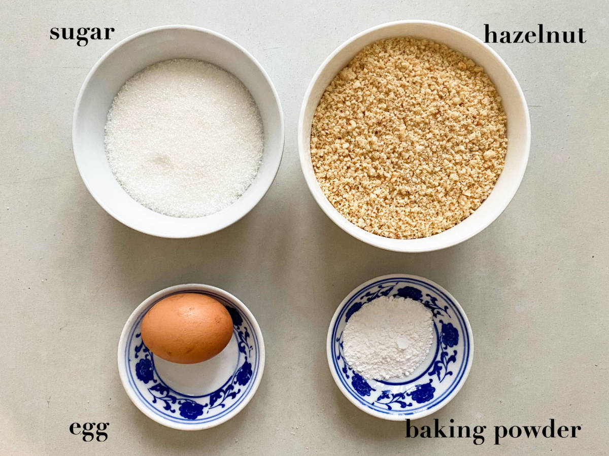 Overhead photo o ingredients: sugar, hazelnuts, eggs, baking powder.