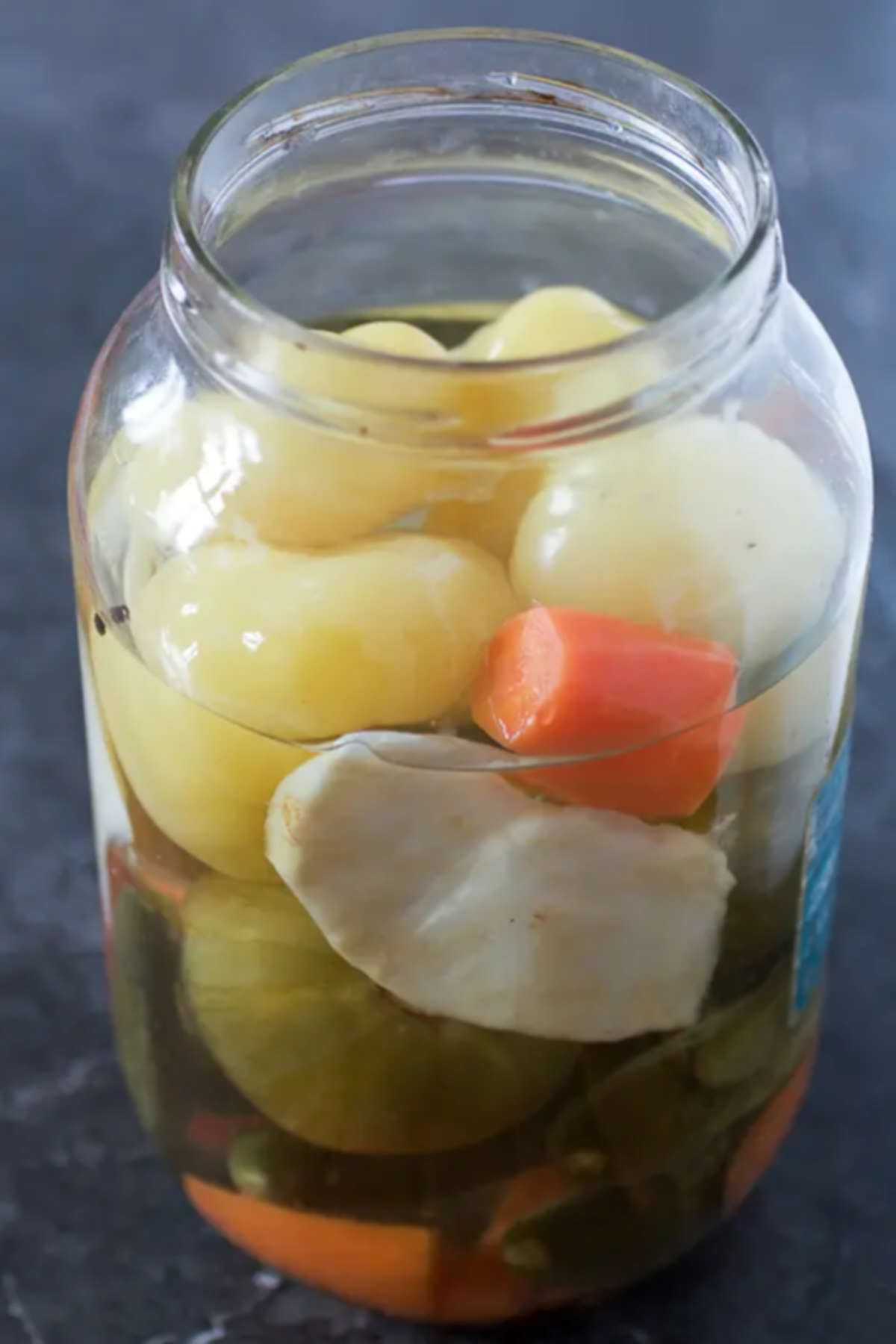 Jar filled with different pickled veggies on a gray background. 