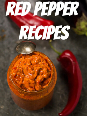 Ajvar in a jar and two red bell peppers (roga peppers) on marble gray background, pictured overhead.